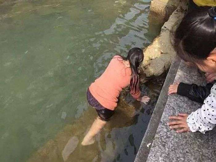 Китаянка пірнула в крижану воду, щоб дістати впав iPhone (4 фото)